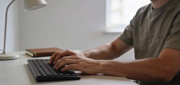 Homme assis a un bureau tapant sur clavier