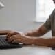 Homme assis a un bureau tapant sur clavier