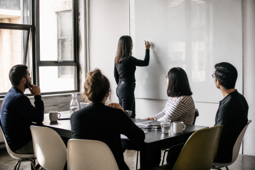 Equipe reunie autour une table avec tableau blanc