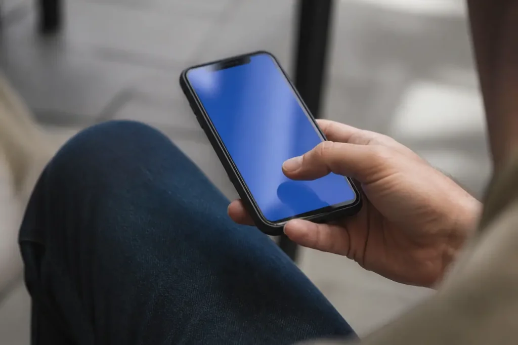 Main tenant un smartphone affichant une application bleue